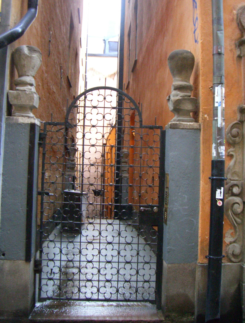 A narrow street in Stockholm Old Town with a metal scrollwork gate