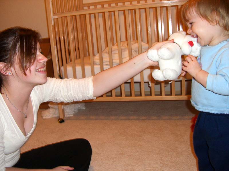 With a babysitter, playing with a white stuffed dog