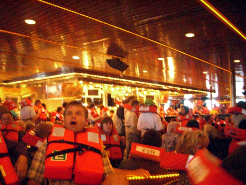 People practice putting on life jackets on a cruiseboat in a mandatory drill